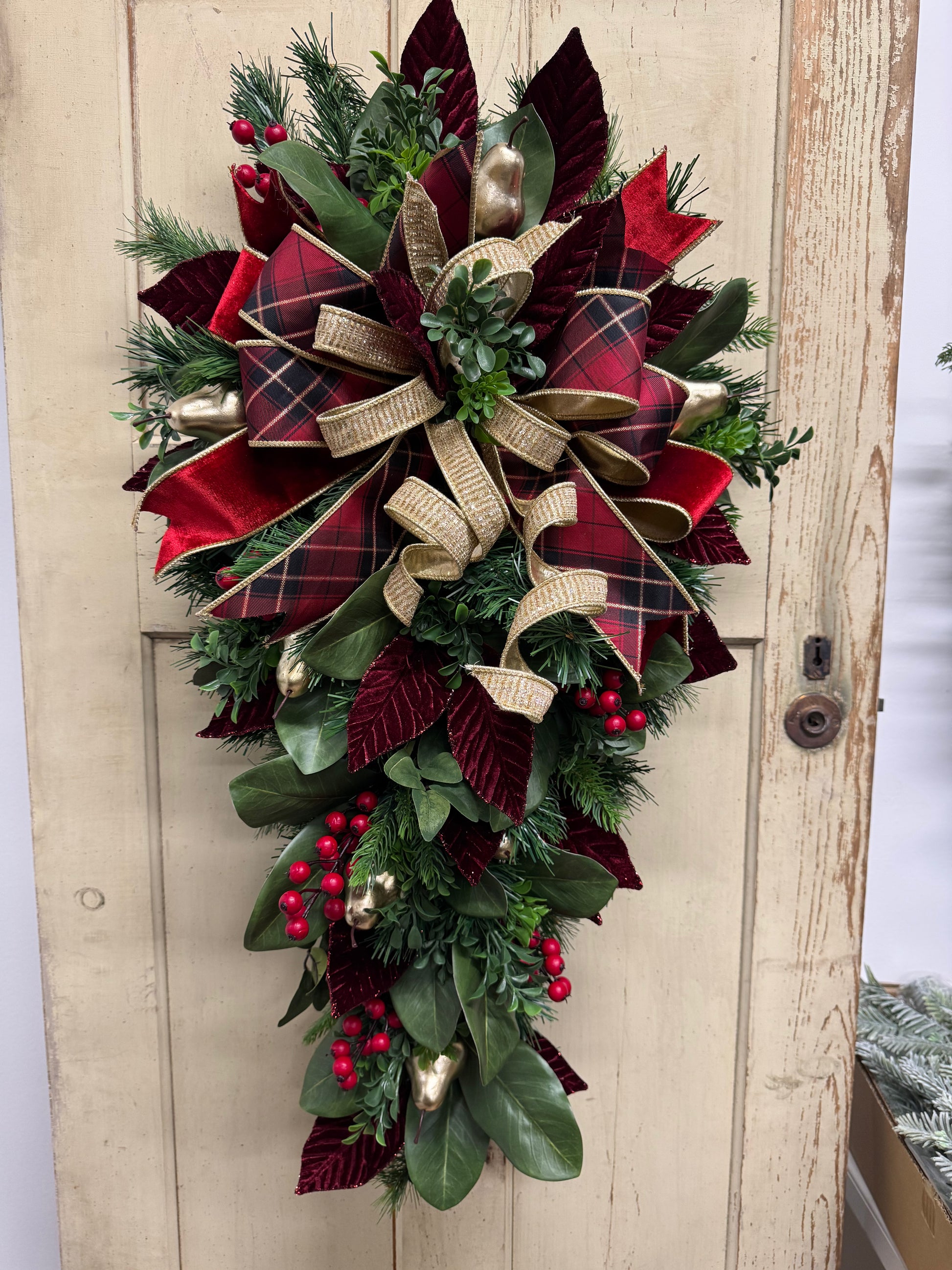 Christmas swag detail with red berries, gold pears, green magnolia leaves, pine, boxwood, and burgundy leaves.”