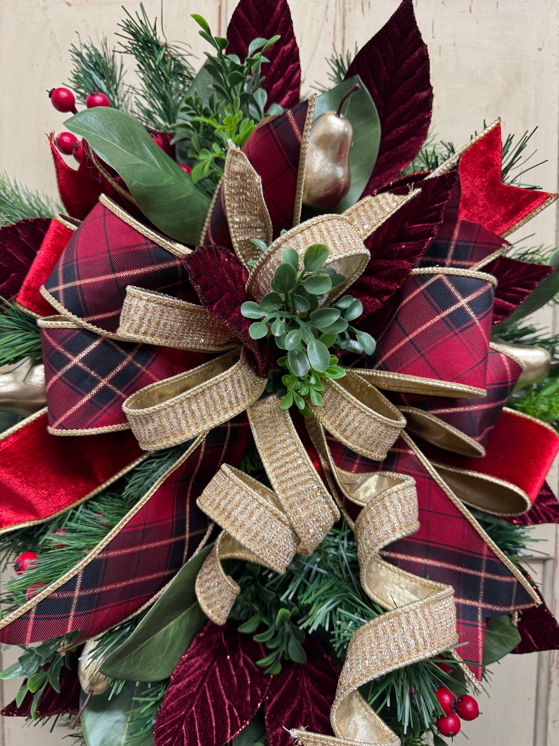 close up of Christmas swag detail with red berries, gold pears, green magnolia leaves, pine, boxwood, and burgundy leaves.”