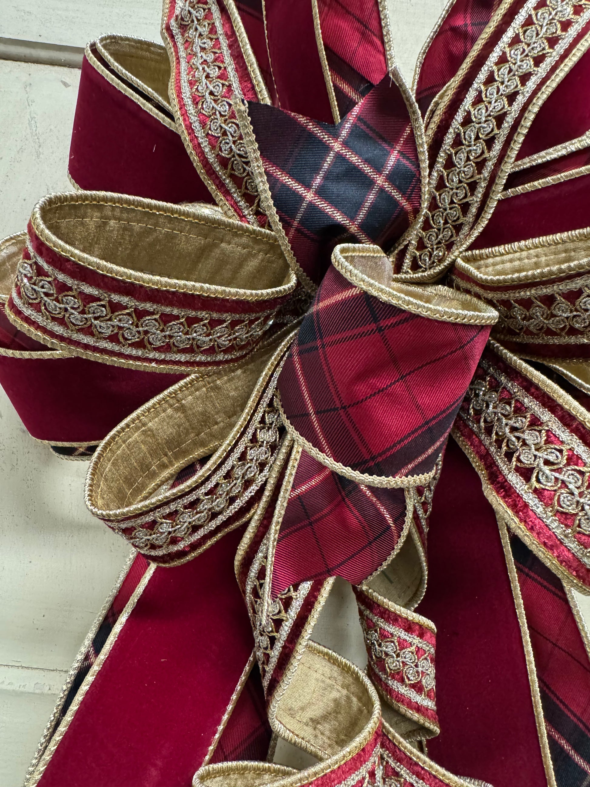 Red plaid and burgundy velvet Christmas bow with gold embroidered ribbon, layered loops, and cascading curled tails.”