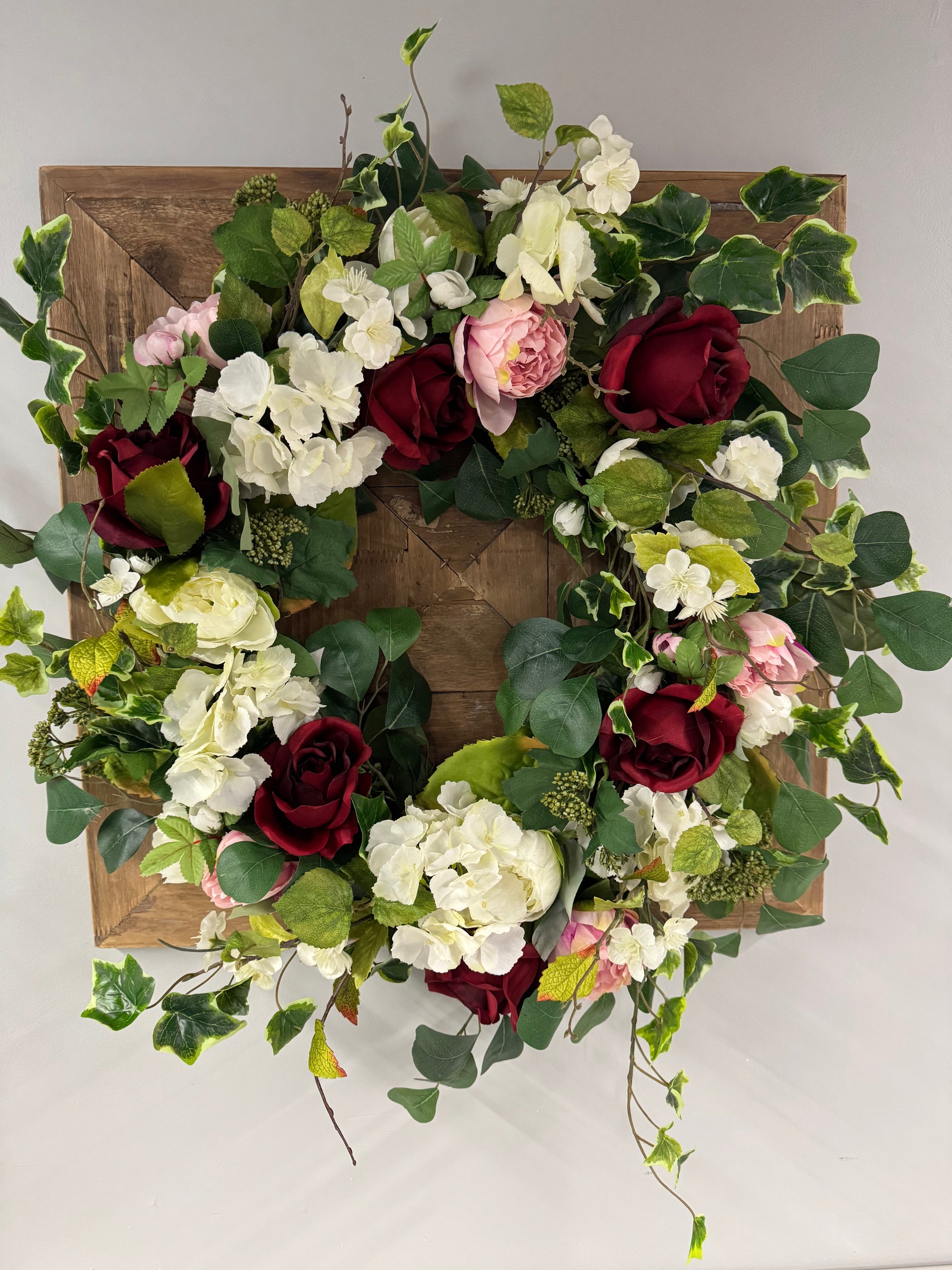 handmade wreath with red roses, white and pink peony and green ivy 