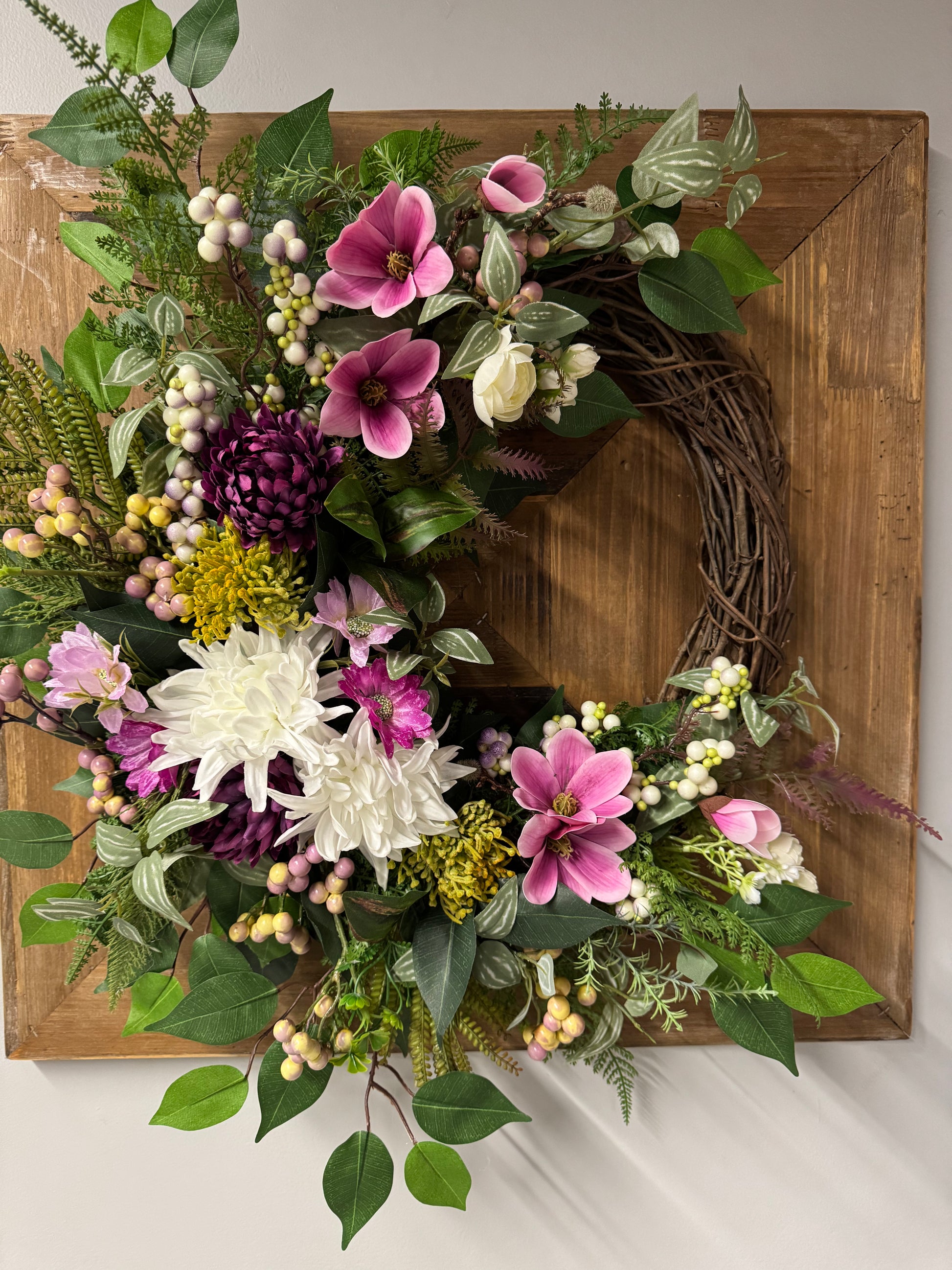 Handcrafted spring wreath featuring vibrant violet blooms and fresh greenery.