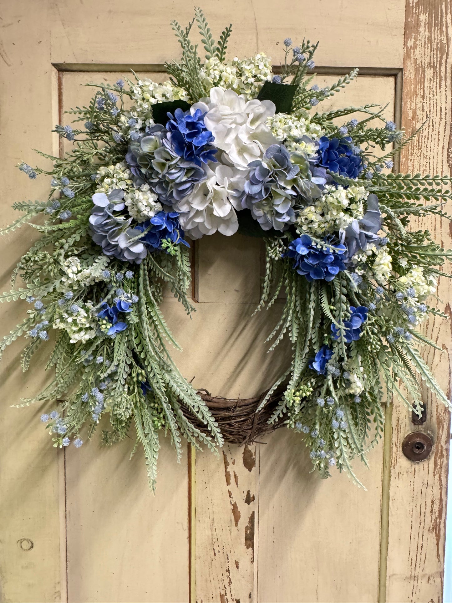 Isla Blue hydrangea wreath with soft faux blue hydrangea blooms and lush greenery on a natural base, perfect for front doors and coastal-inspired year-round home decor"
