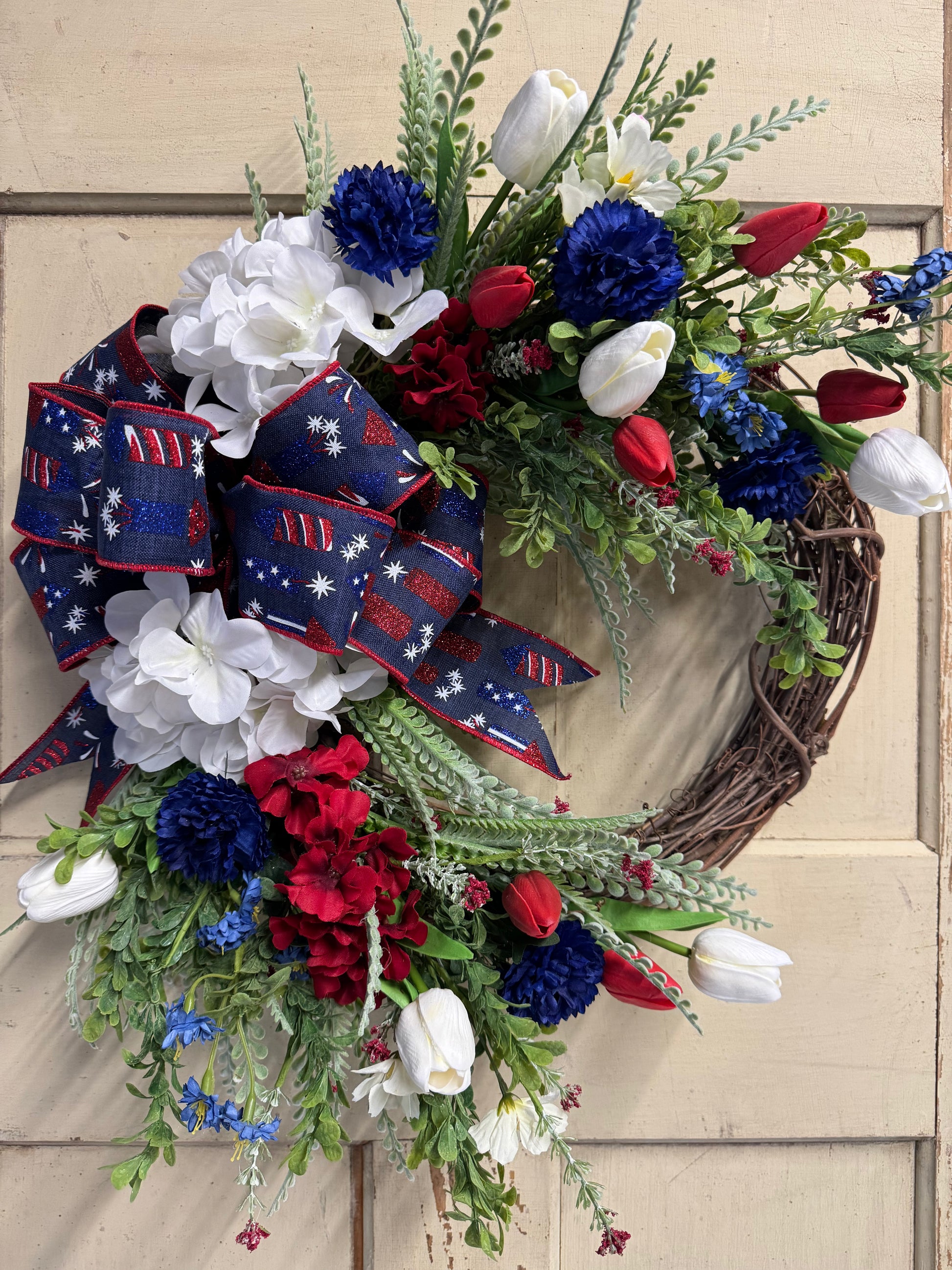 23 inch Firecracker Sally patriotic crescent wreath with red, white, and blue florals and a decorative bow, perfect for front doors and Fourth of July home decor"