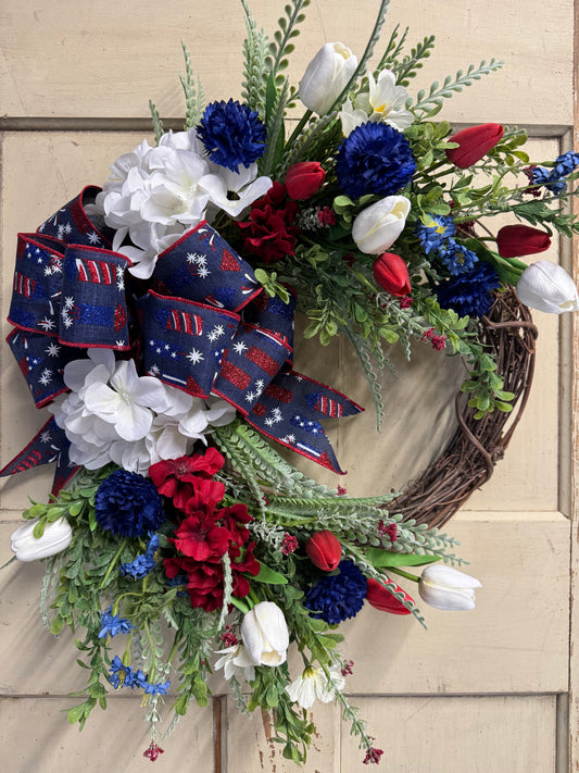23 inch Firecracker Sally patriotic crescent wreath with red, white, and blue florals and a decorative bow, perfect for front doors and Fourth of July home decor"