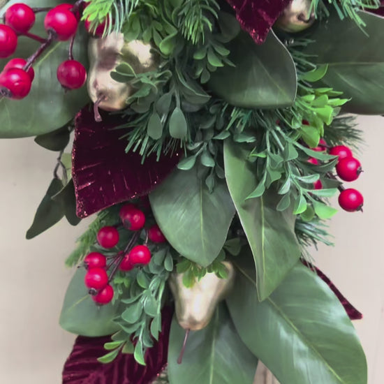 video of Christmas swag detail with red berries, gold pears, green magnolia leaves, pine, boxwood, and burgundy leaves.”
