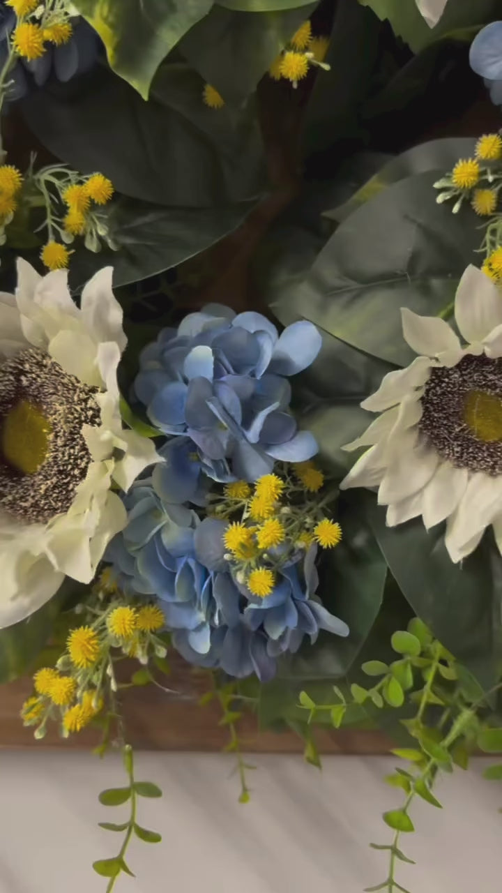 video of Sunny blue hydrangea wreath with white sunflowers and yellow baby's breath on rustic wood frame for front door"