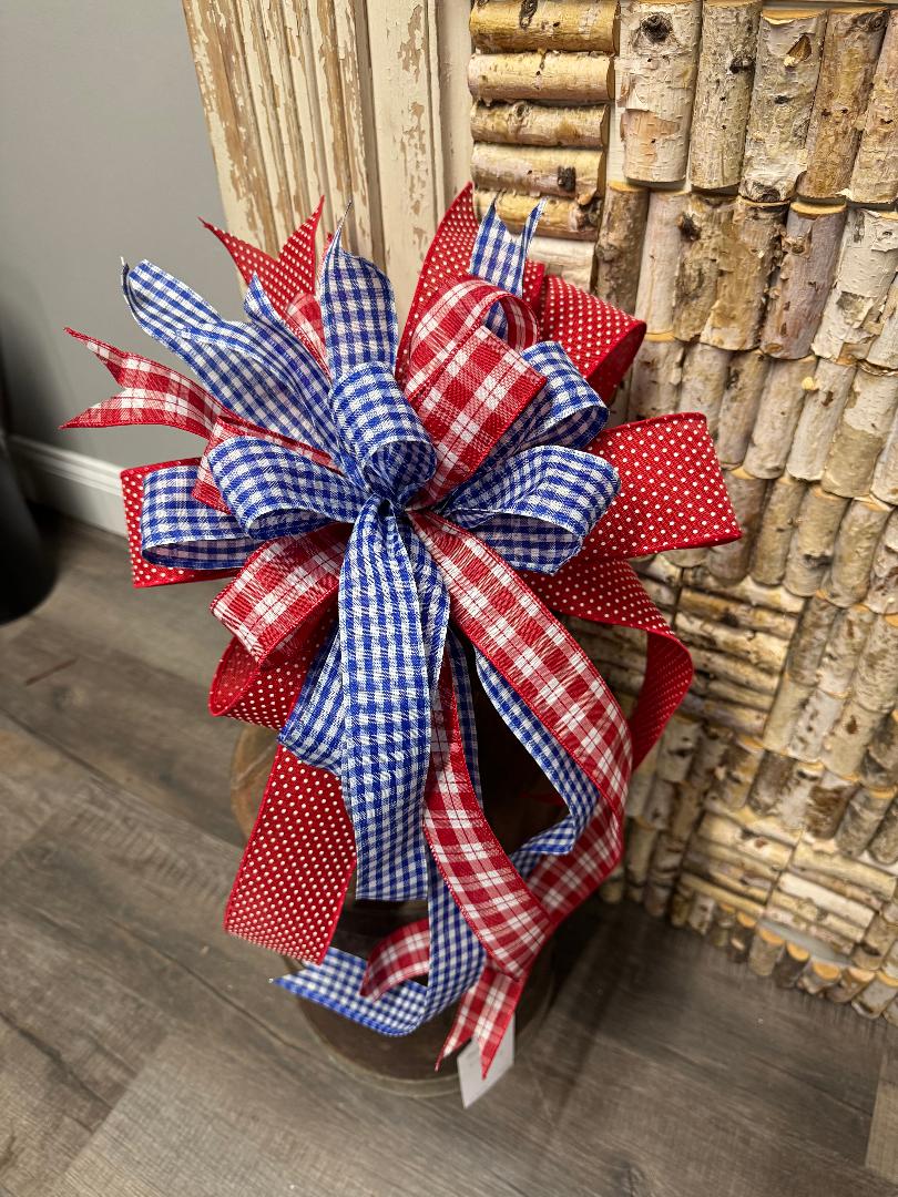 Handcrafted patriotic bow with red satin polka dot ribbon, red and white plaid, and blue and white plaid ribbon, measuring 13 by 19 inches"