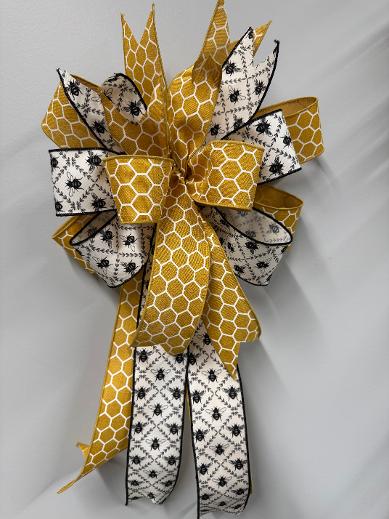 Handcrafted black and gold bee bow, 13 by 19 inches, made with gold honeycomb and black bee trellis ribbon