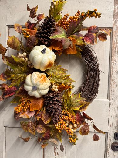 Julia handmade fall wreath on a grapevine base with white pumpkins, pinecones, orange and cream berries, and mixed autumn foliage in rust, burgundy, and gold, hanging on a white door