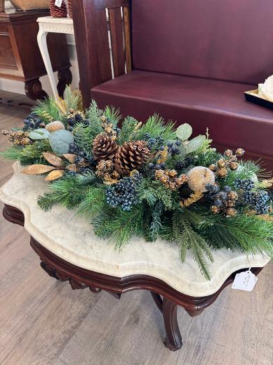 Merry Winterberry Christmas centerpiece with green pine, eucalyptus, cream beaded apples, blue berries, pinecones, and gold accents.”