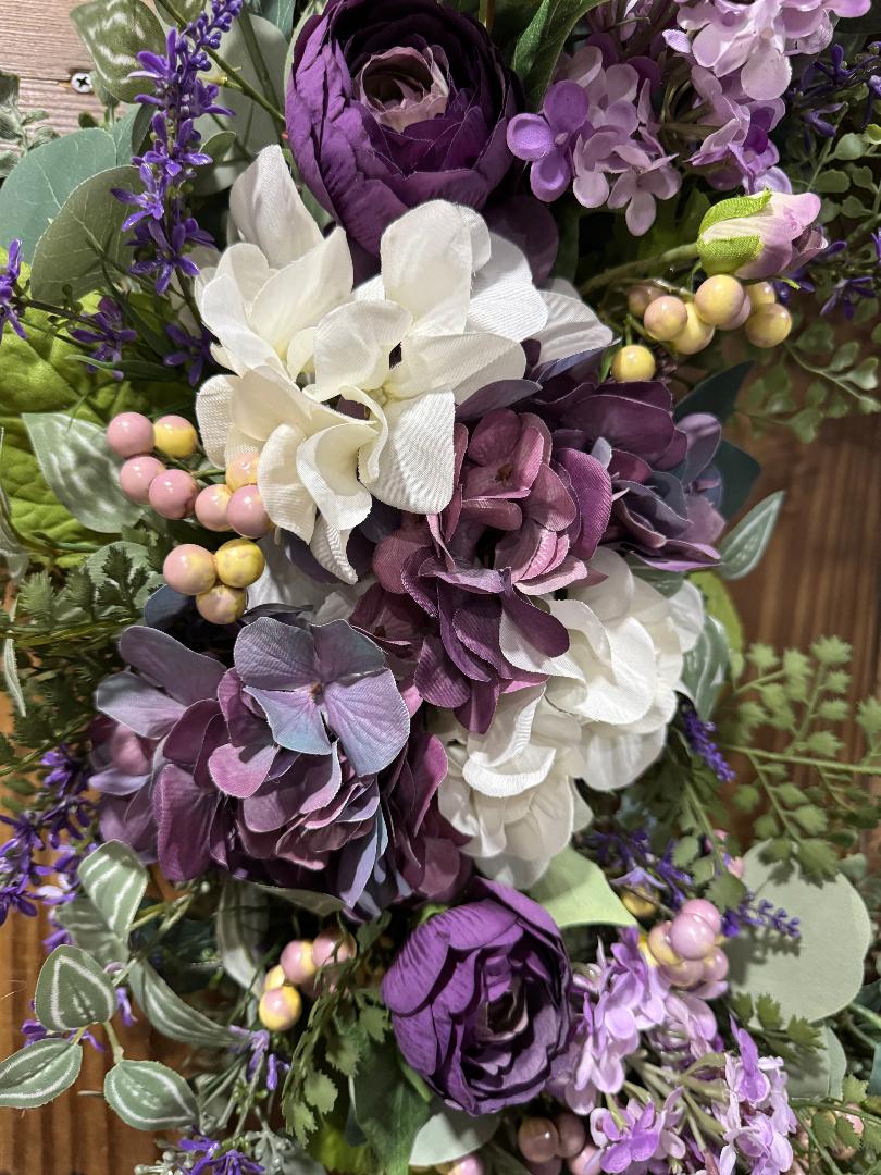 Bouquet of purple and white flowers with green leaves on a wooden surface