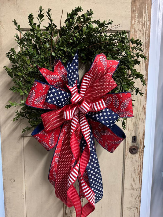 Patriotic boxwood wreath with red, white, and blue accents and lush faux greenery, perfect for Fourth of July and Memorial Day decor"