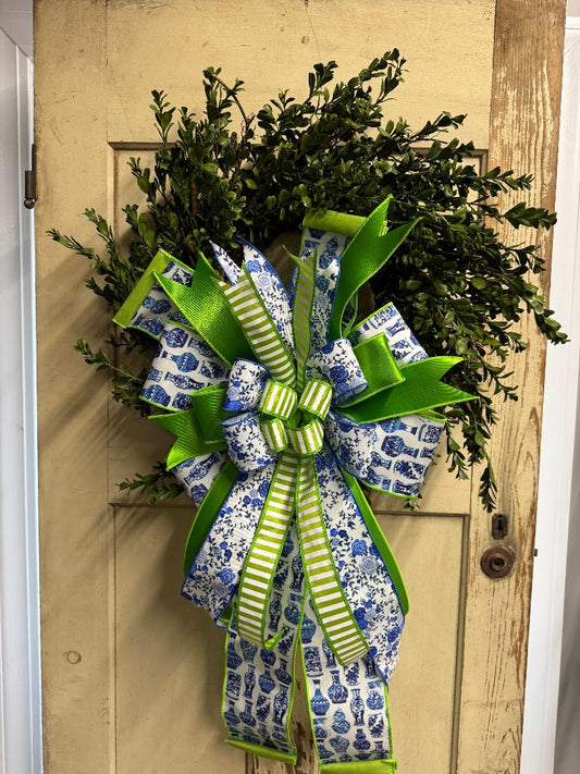 Boxwood wreath with a blue and green decorative bow featuring lush faux greenery and vibrant ribbon accents"