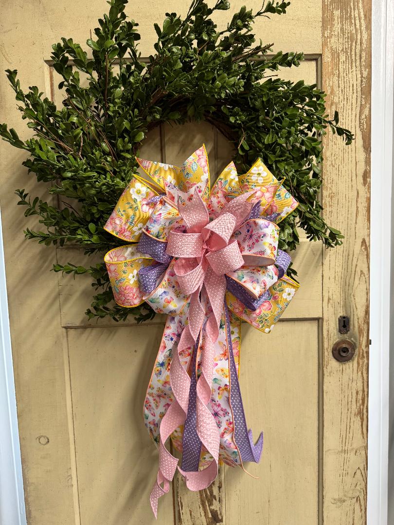 Boxwood wreath with a decorative floral bow featuring lush faux greenery and an elegant ribbon accent"
