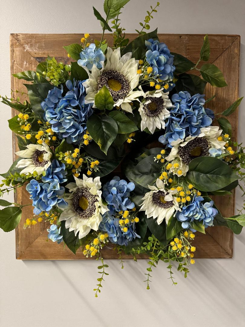 Sunny blue hydrangea wreath with white sunflowers and yellow baby's breath on rustic wood frame for front door"